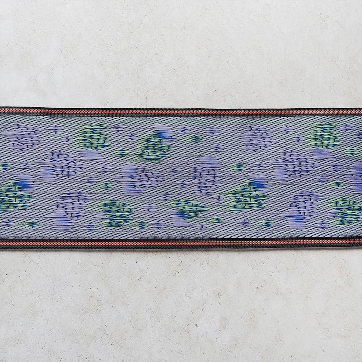 a patterned fabric with a blue and green color scheme, displayed on a white surface.